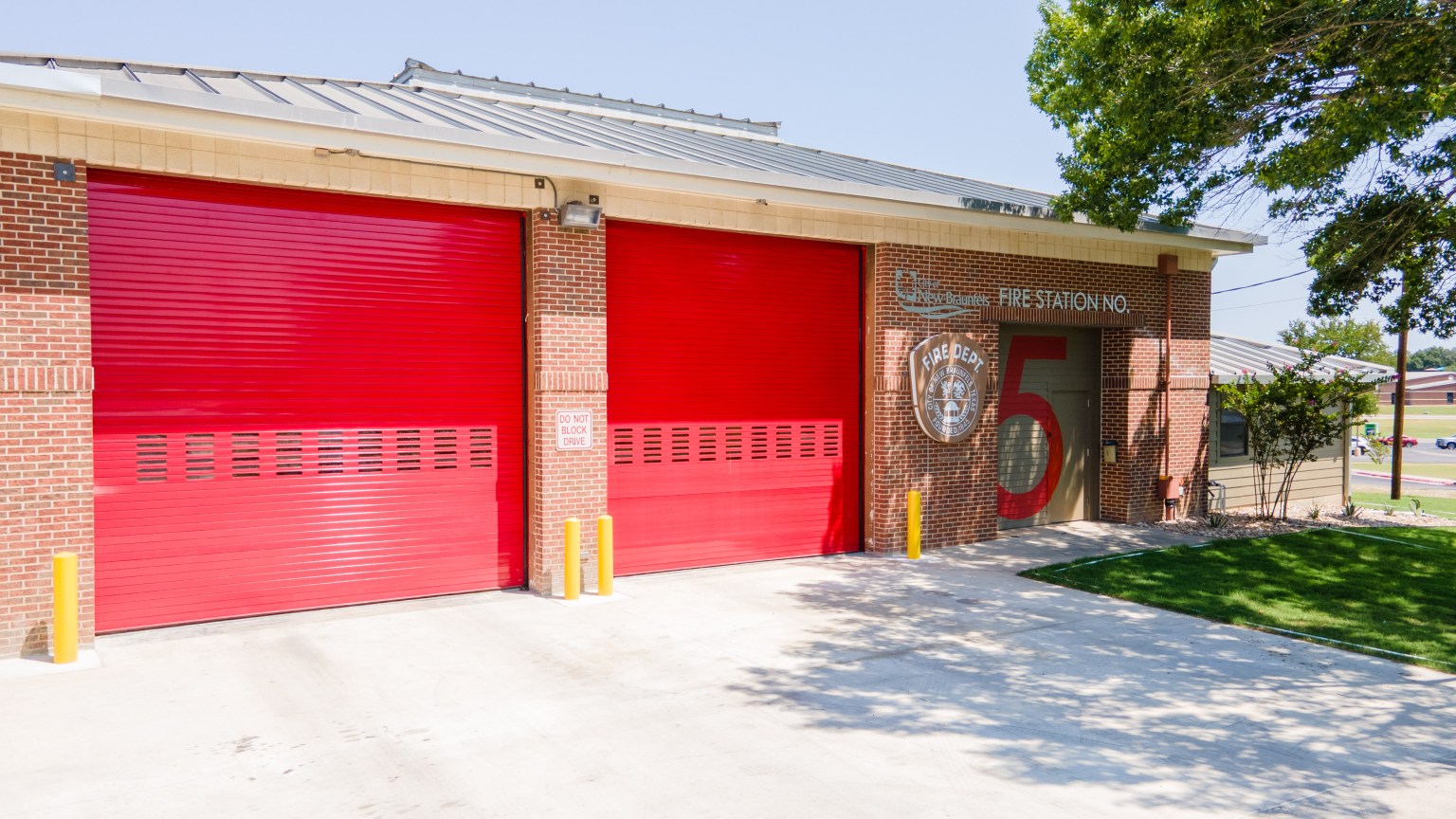 Fire station with bright red garage doors, brick exterior, and a circular department emblem near the entrance.