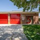 Front view of a brick fire station with bright red garage doors and a large number 5 on the side under a clear blue sky
